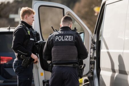 Zwei Polizisten stehen vor einem Transporter.