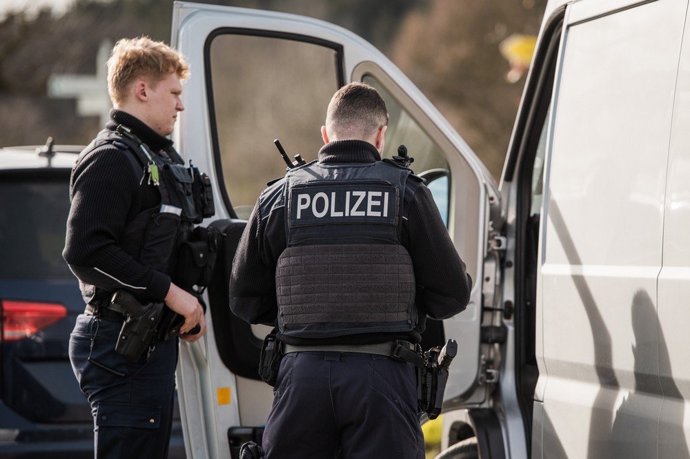 Zwei Polizisten stehen vor einem Transporter.