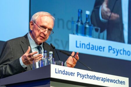 Ein älterer Mann steht an einem Rednerpult.