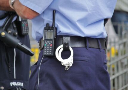 Ein Polizist von hinten mit Handschellen.