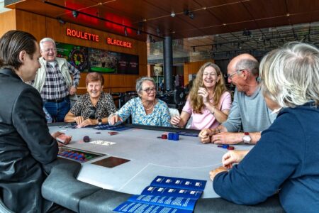 Mehrere Menschen sitzen um einen Roulette-Tisch.