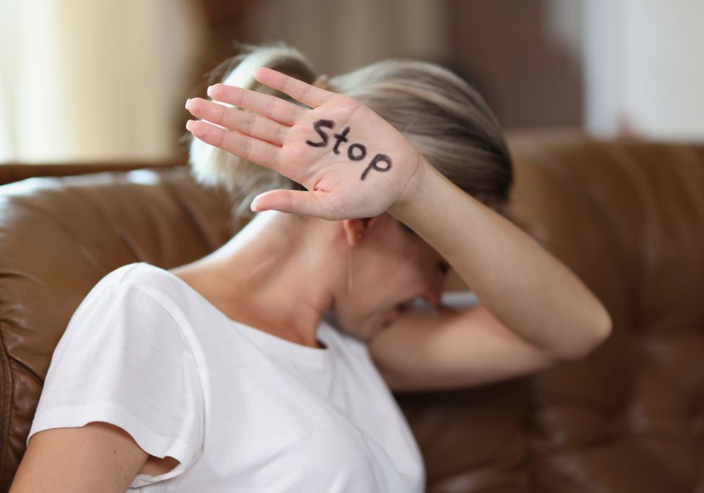 Eine Frau hält eine Hand vors Gesicht, auf der "Stopp" steht.