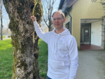 Ein Mann lehnt an einem Baum.