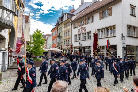 Feuerwehrmänner ziehen in einem Festumzug durch die Straßen.