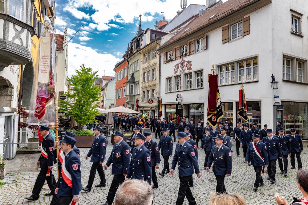 Feuerwehrmänner ziehen in einem Festumzug durch die Straßen.