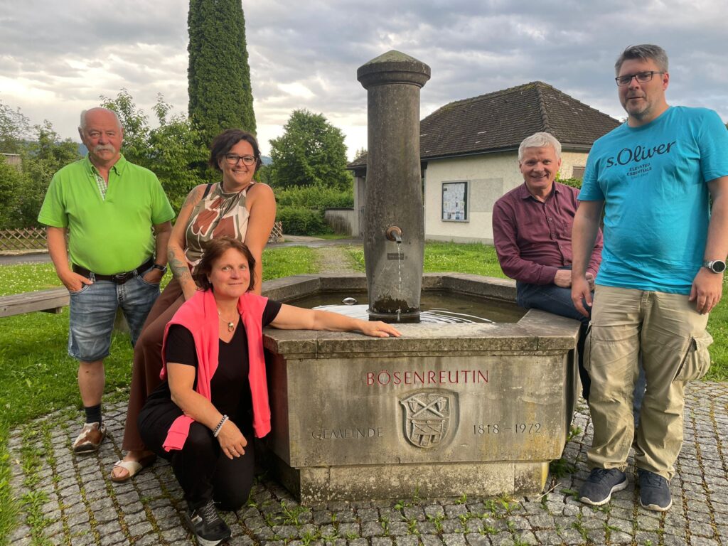 Fünf Menschen stehen um einen Brunnen herum.