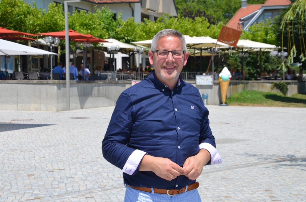 Ein Mann im blauen Hemd auf einem gepflasterten Platz.