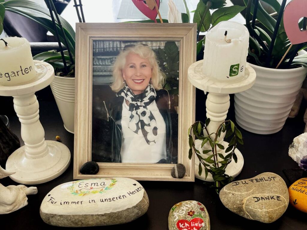 Ein Portrait von einer Frau, daneben Kerzen und bemalte Steine.