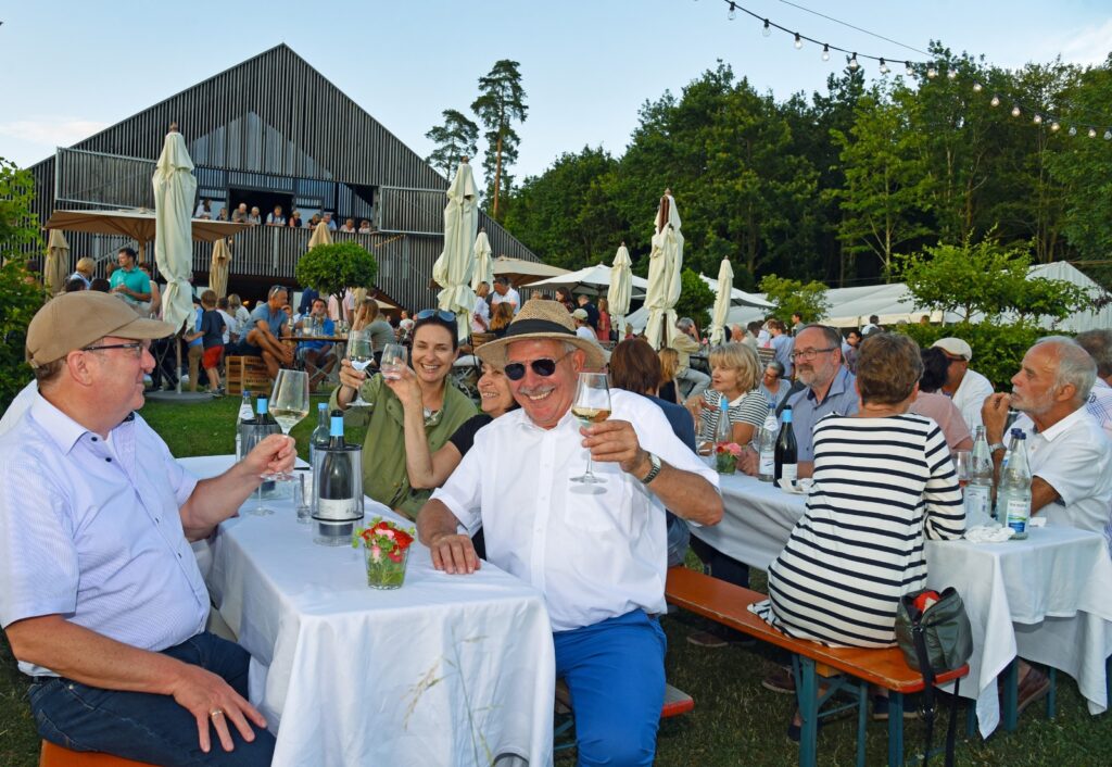 Viele Menschen an Bierbänken mit Wein.