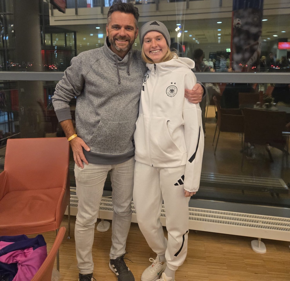 Ein Mann hält eine junge Frau in Sportklamotten im Arm.