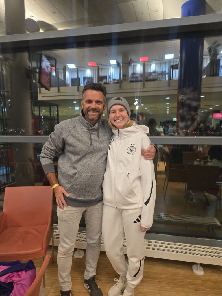 Ein Mann hält eine junge Frau in Sportklamotten im Arm.
