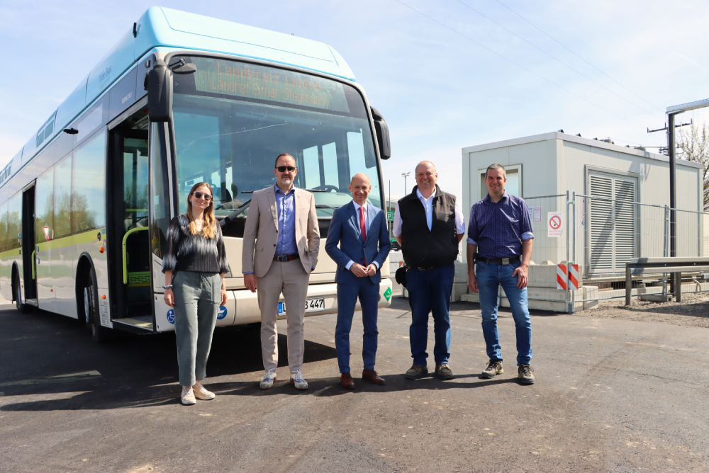 Fünf Menschen stehen vor einem Bus.