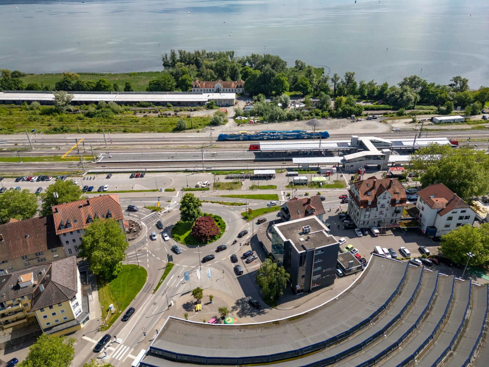 Luftbild von einem Kreisverkehr, Bahngleisen und einem großen See.