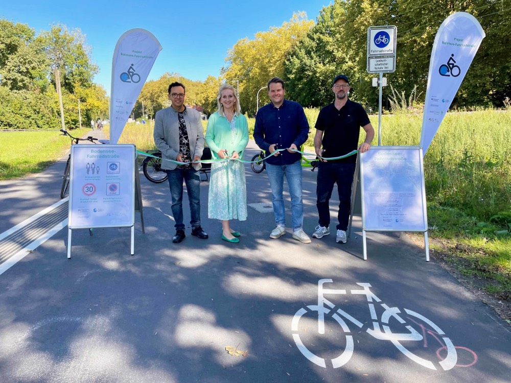 Vier Menschen schneiden ein Band durch.