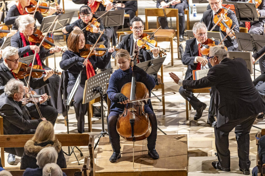 Ein Orchester mit Cellistin in der Mitte.